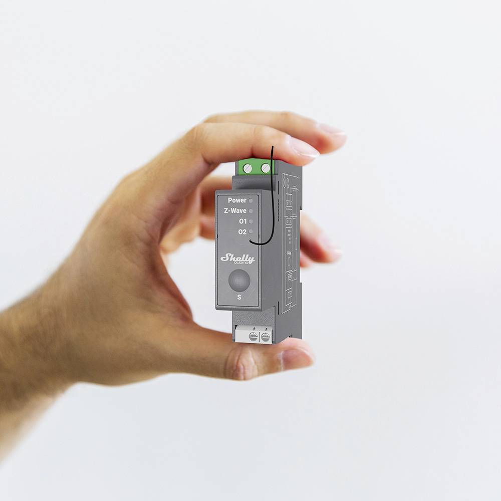 Eine Hand hält ein kleines rechteckiges elektronisches Gerät mit der Aufschrift 'Froggy F'. Oben sind zwei LED-Anzeigen zu sehen.