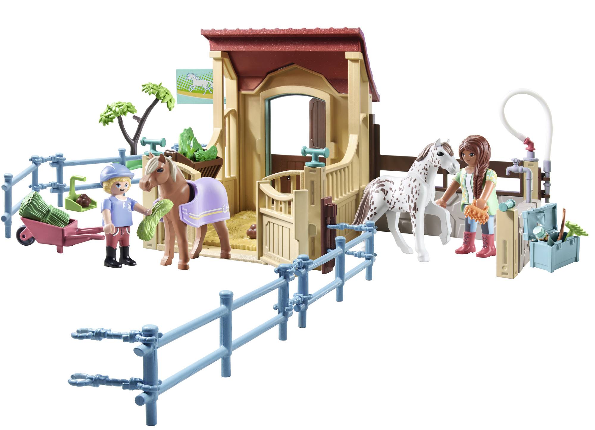 Zwei Kinderfiguren füttern ein braunes und ein weißes Pferd im offenen Stall. Im Hintergrund ist eine Heugabel und ein Futterkarren.