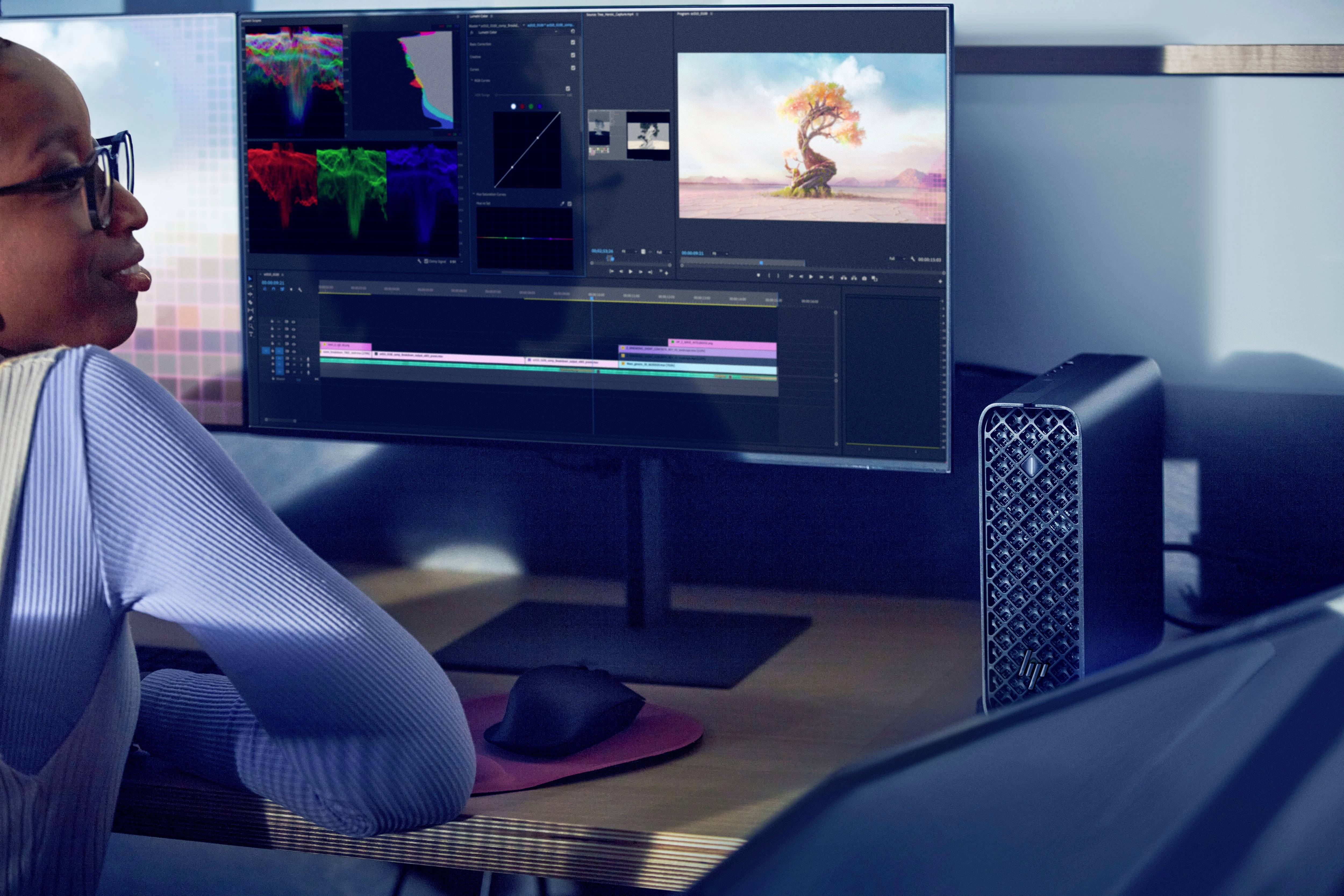 Eine Person bearbeitet ein Video an einem Computer. Auf dem Bildschirm sind Videobearbeitungssoftware und ein Landschaftsbild sichtbar.