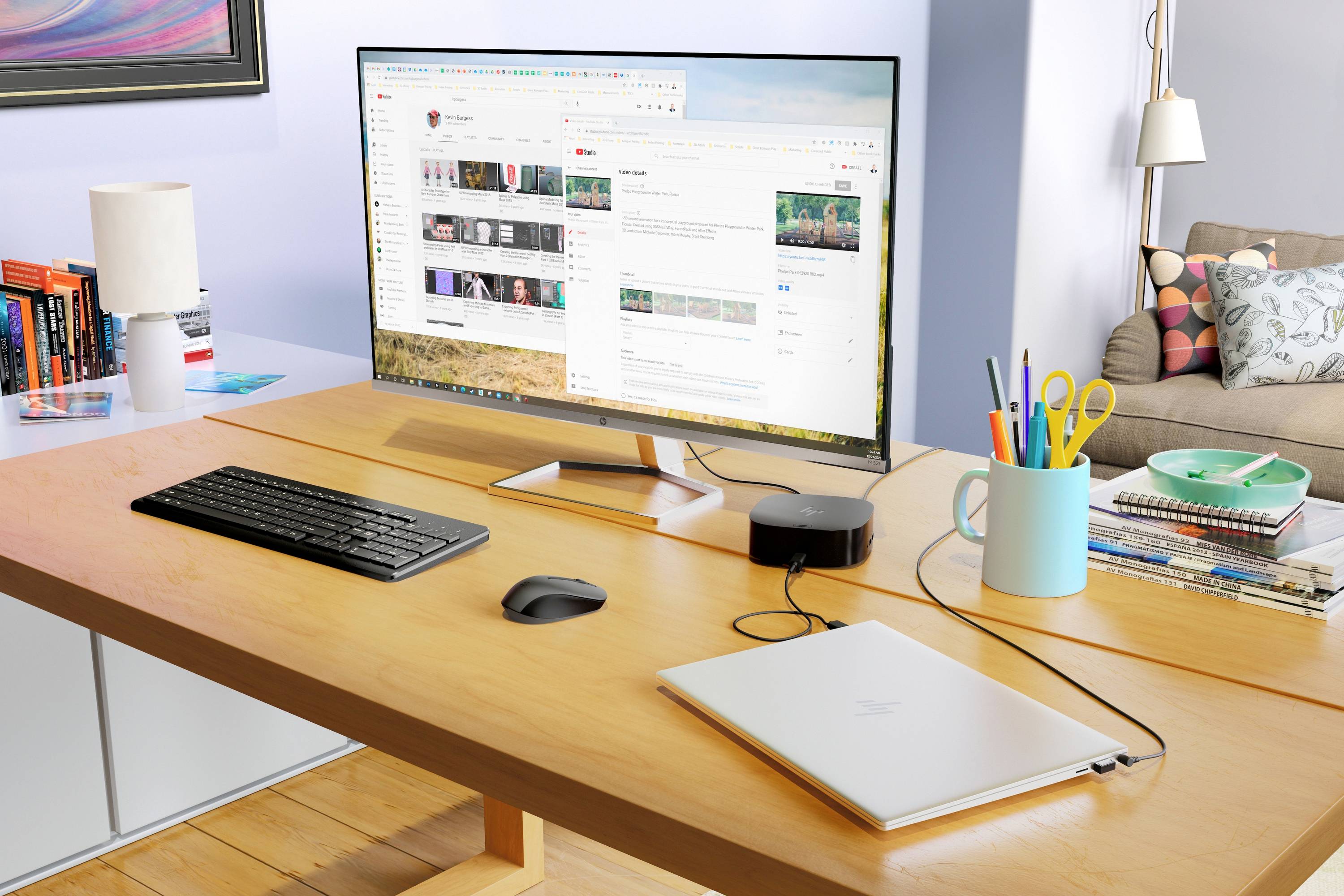Ein Schreibtisch in einem Büro mit einem großen Monitor, auf dem eine Website angezeigt wird, eine Tastatur, Maus, Laptop und Schreibtischzubehör.