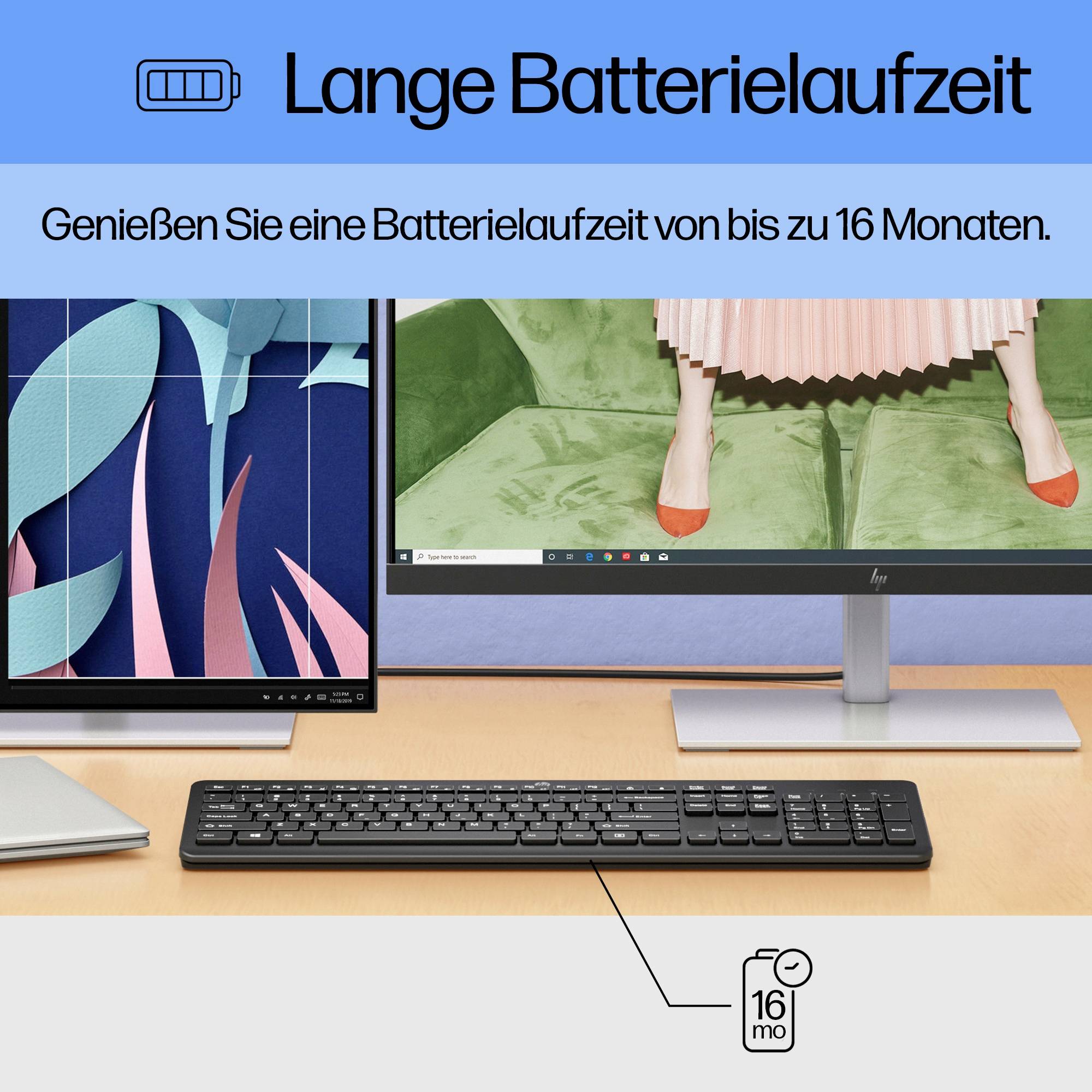 Eine Computermaus und Tastatur auf einem Tisch vor zwei Monitoren. Text oben: 'Lange Batterielaufzeit, bis zu 16 Monate'.