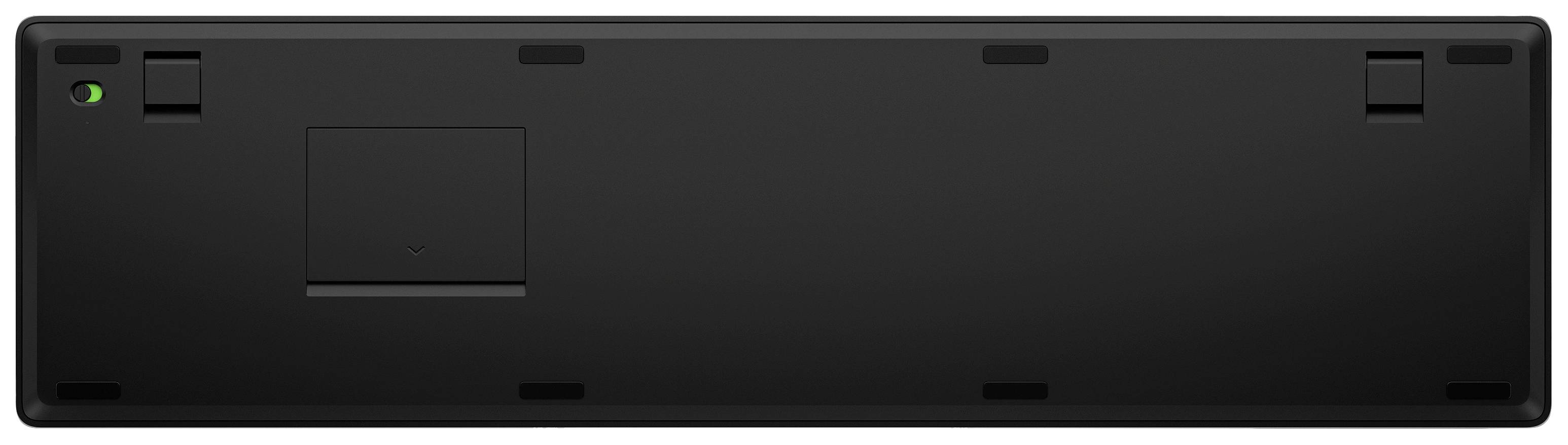 Rückseite einer schwarzen Tastatur mit Fach für Batterien und rutschfesten Füßen.