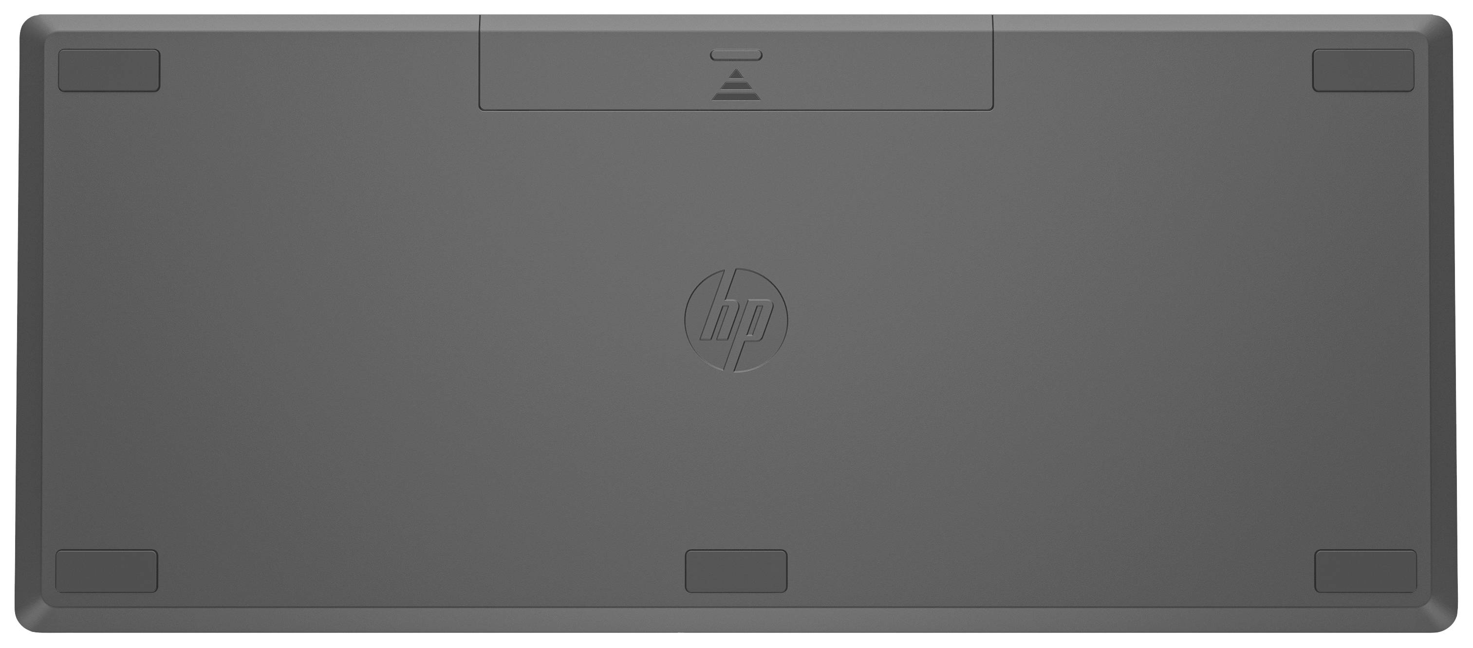 'Rückseite einer schwarzen Tastatur mit Herstellerlogo in der Mitte und kleinen rutschfesten Füßen an den Ecken.'