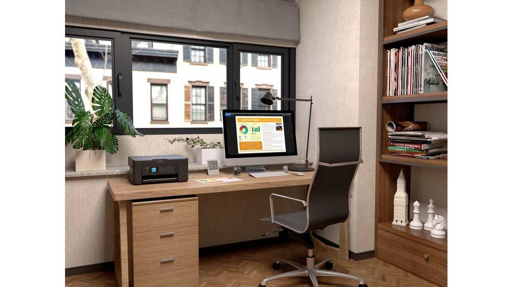 Ein ordentliches Homeoffice mit Schreibtisch, Stuhl, Computerbildschirm mit Diagrammen, Drucker, Pflanze und Bücherregal am Fenster.