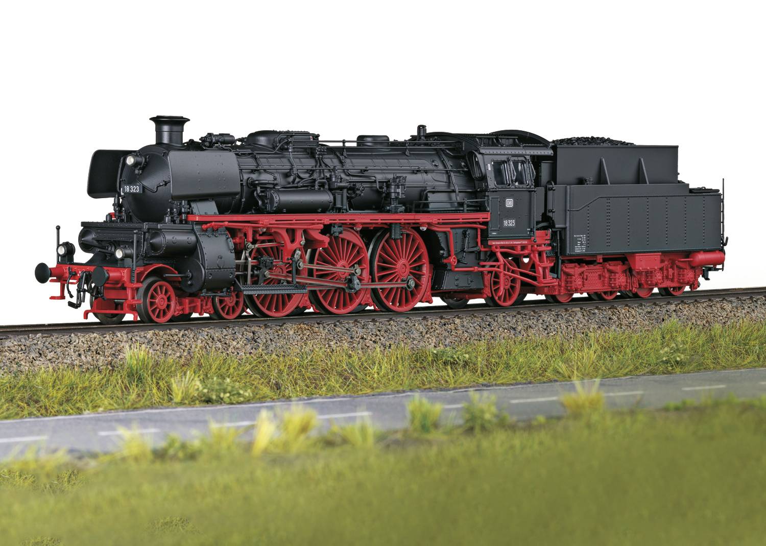 Eine schwarze Dampflokomotive mit roten Rädern fährt auf Bahngleisen. Im Vordergrund ist eine grasbewachsene Fläche zu sehen.