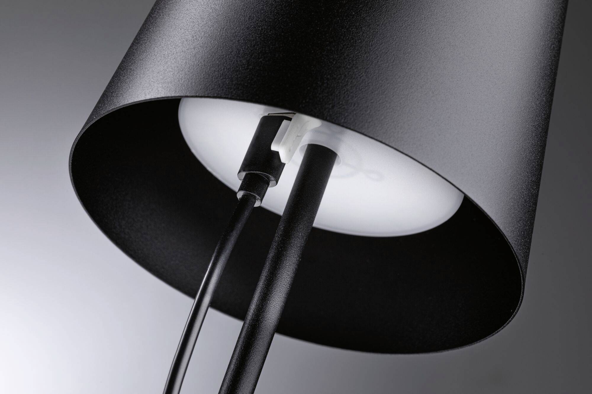 Nahaufnahme einer modernen schwarzen Lampe mit sichtbarem Kabel und Schirm, die eine stilvolle Beleuchtungslösung darstellt.