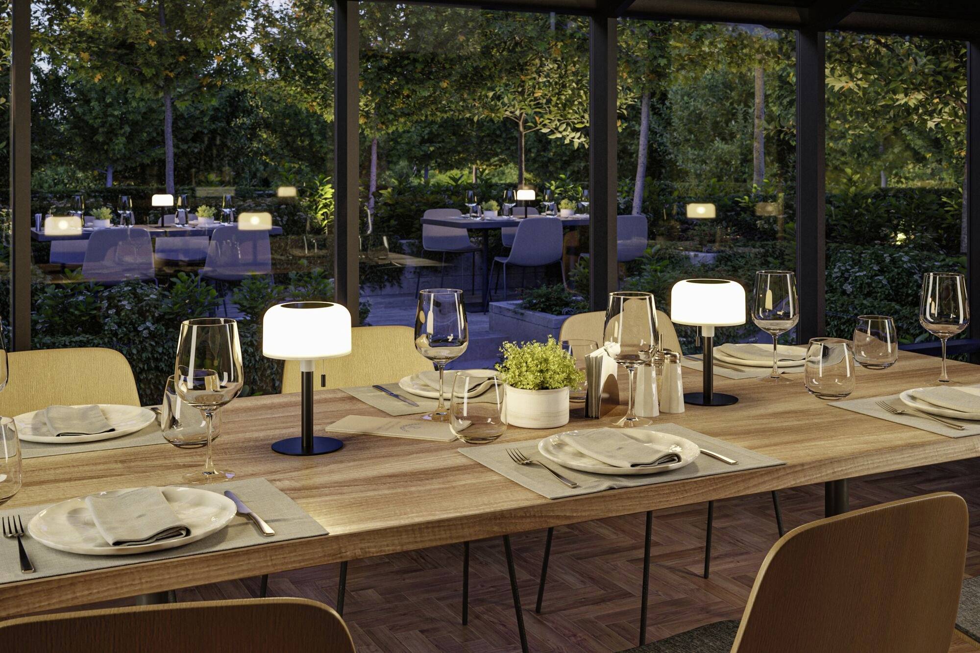 Ein gedeckter Holztisch in einem eleganten Restaurant mit Blick auf eine grüne Terrasse. Lichter sorgen für eine warme Atmosphäre.