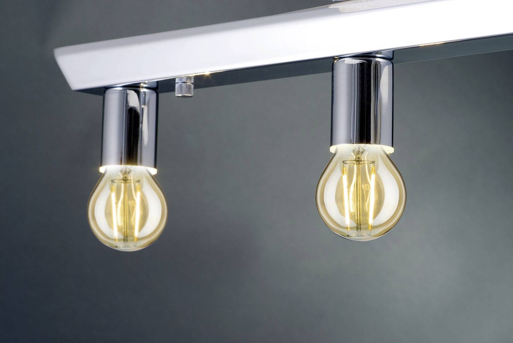 Zwei hängende Glühbirnen mit sichtbaren Filamenten an einer metallischen Halterung, vor einem grauen Hintergrund.