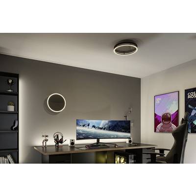 Ein moderner Gaming-Schreibtisch mit gebogenem Monitor und Tastatur. An der Wand hängen Poster, und ein Regal enthält Bücher und Deko.