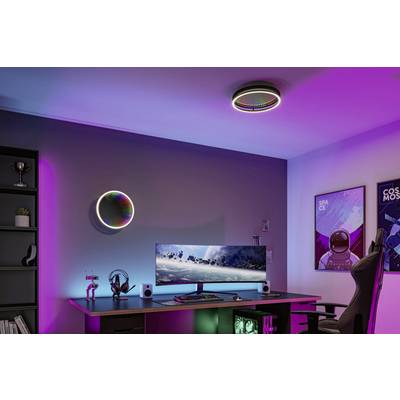 Ein modernes Gaming-Setup in lila und blauer Beleuchtung mit einem großen Monitor, Tastatur und dekorativen Sci-Fi-Postern an der Wand.