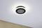 Schwarze, runde Deckenleuchte mit leuchtendem LED-Ring, an weißer Decke montiert über einer beigen Wand. Modernes Design.