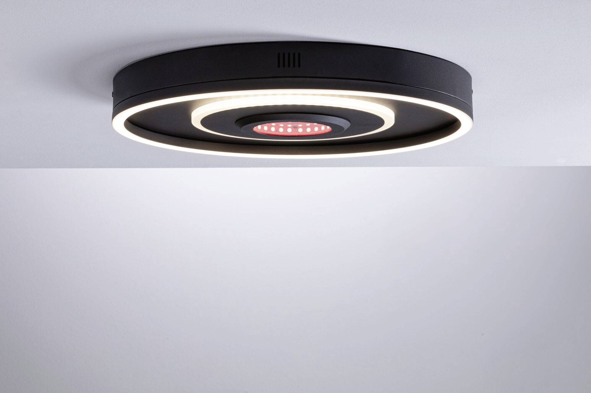 Runde, moderne Deckenleuchte in Schwarz mit LED-Ring und rotem Licht in der Mitte, montiert an einer weißen Decke.