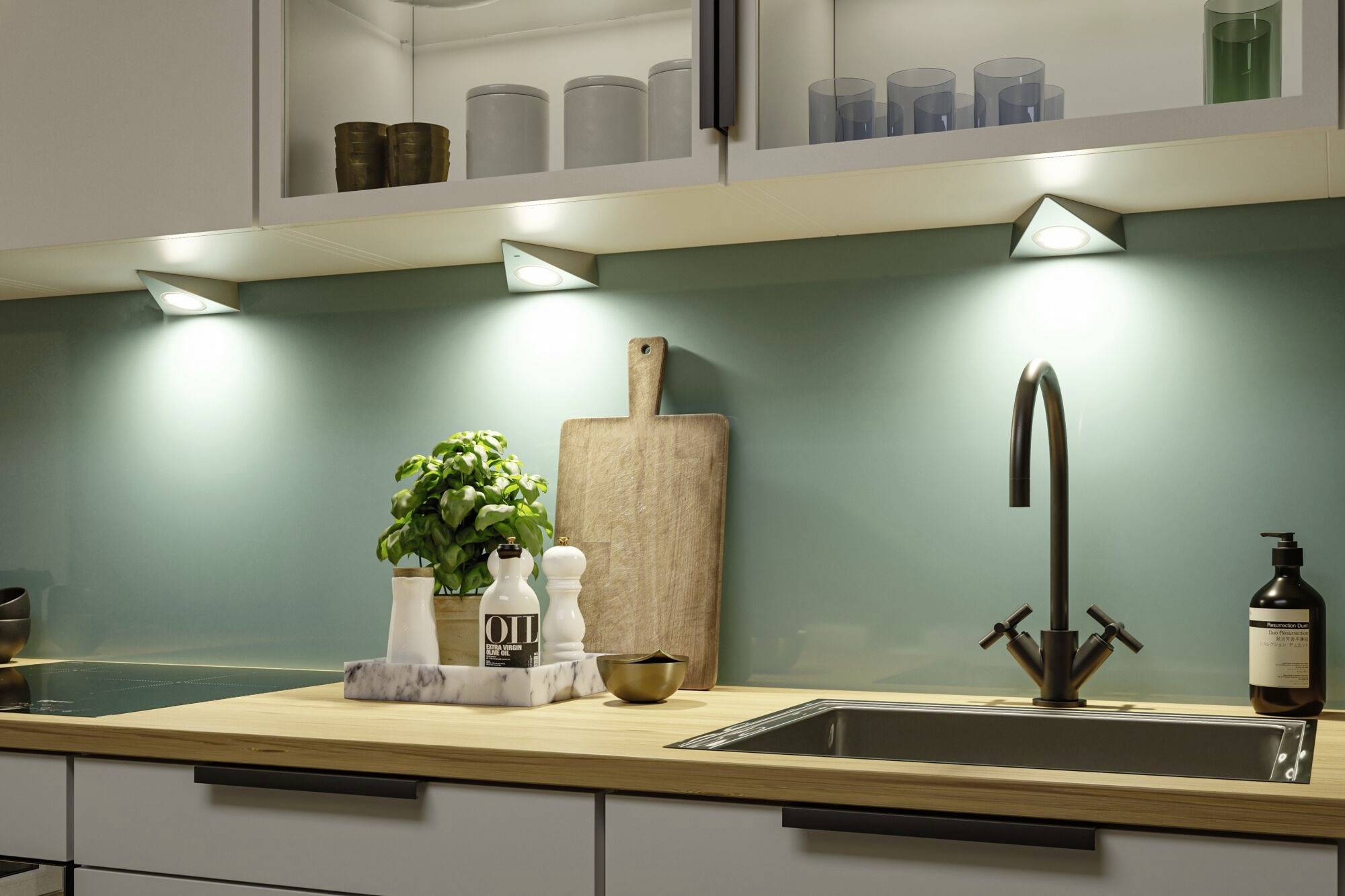 Moderne Küche mit hellblauer Rückwand und Holzarbeitsplatte. Unterleuchten beleuchten das Regal mit Geschirr, ein Schneidebrett und Basilikumtopf neben der Spüle.