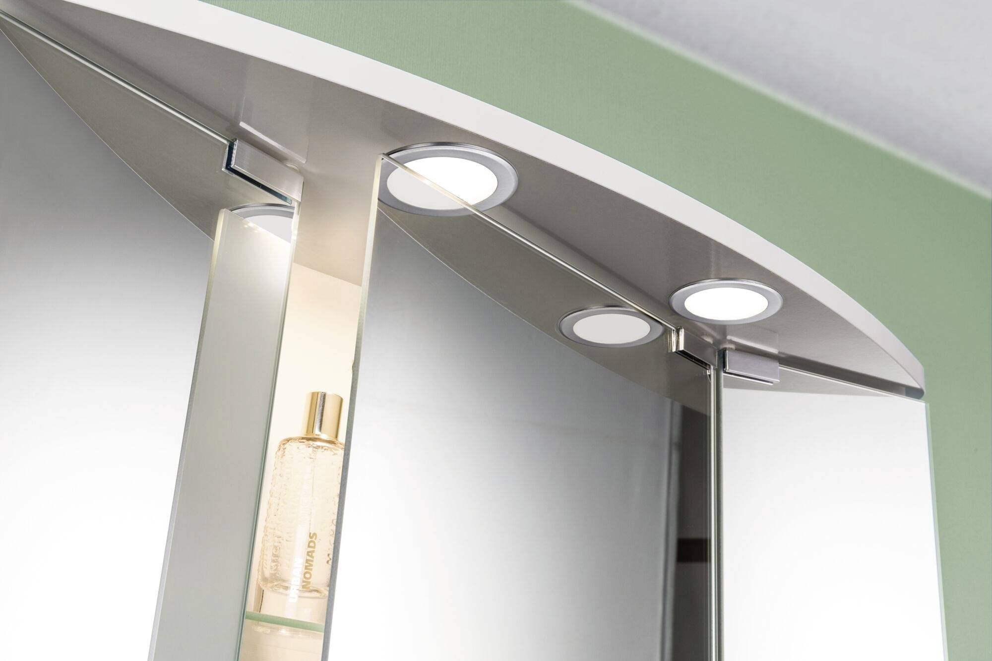 Spiegelschrank mit integriertem Licht, zeigt Parfümflasche auf Glasregal.