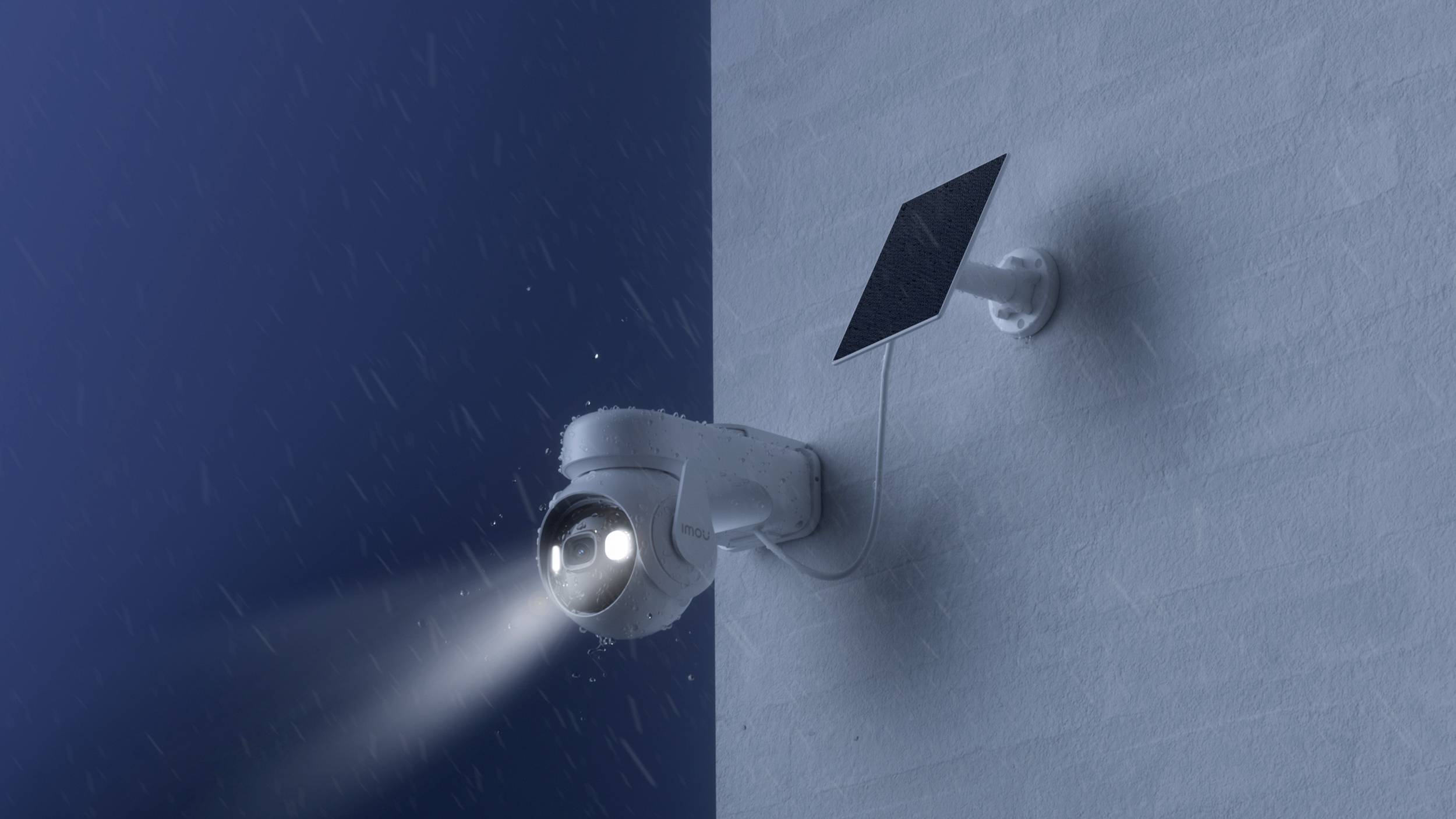 Überwachungskamera bei Nacht an einer Wand montiert, mit angeschlossenem Solarpanel, beleuchtet einen Bereich bei Schneefall.