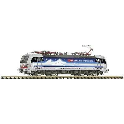Ein Güterzug mit der Aufschrift 'SBB Cargo International' fährt auf Gleisen. Die Lokomotive zeigt ein Bergmotiv auf der Seite.