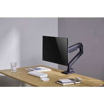 Ein Schreibtisch mit Monitor auf einem verstellbaren Arm, Tastatur, Maus, Notizbüchern und einem Glas. Moderne, minimalistische Einrichtung.