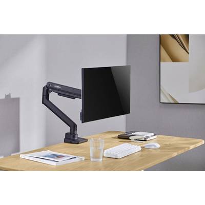 Ein Schreibtisch aus Holz mit einem schwarzen Monitor an einem verstellbaren Arm. Darauf eine Tastatur, Maus, Glas Wasser und zwei Bücher.