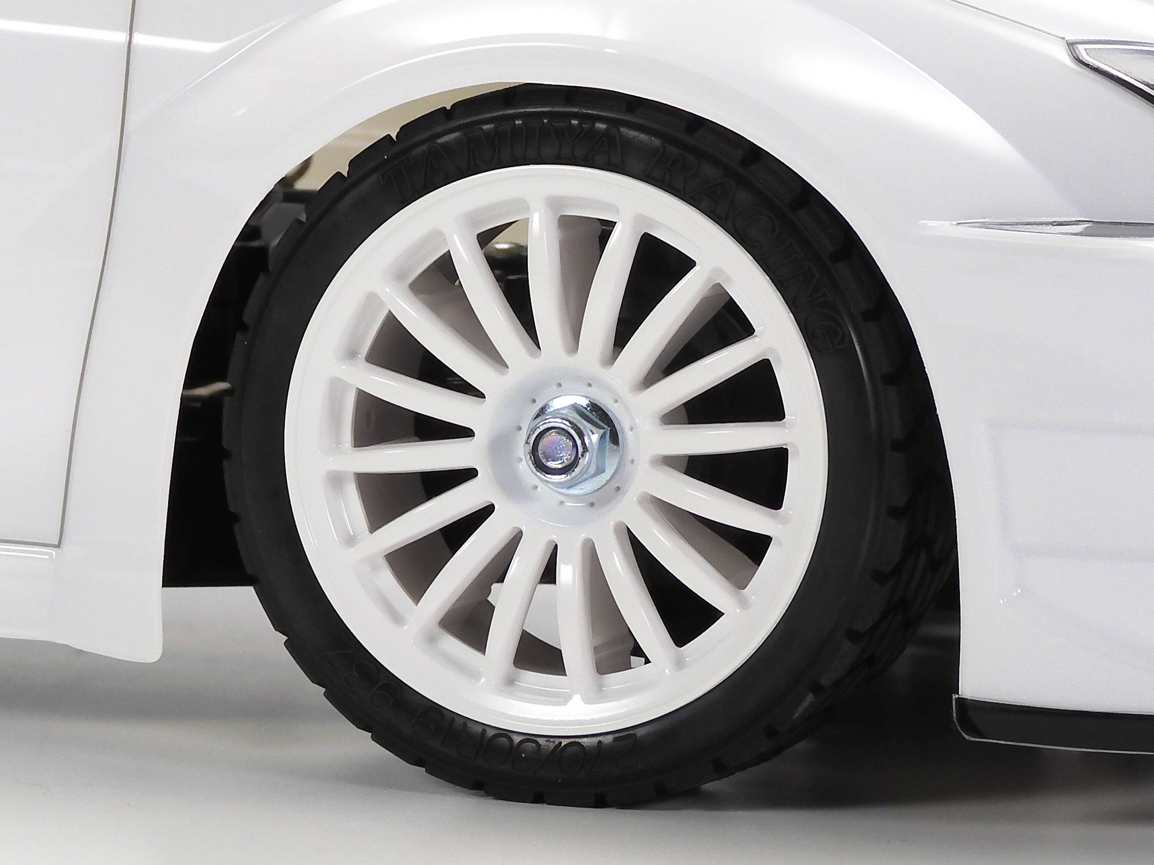Nahaufnahme eines weißen Autoreifens mit einer mehrspeichigen Felge auf hellem Untergrund. Der Reifen ist sauber und glänzend.