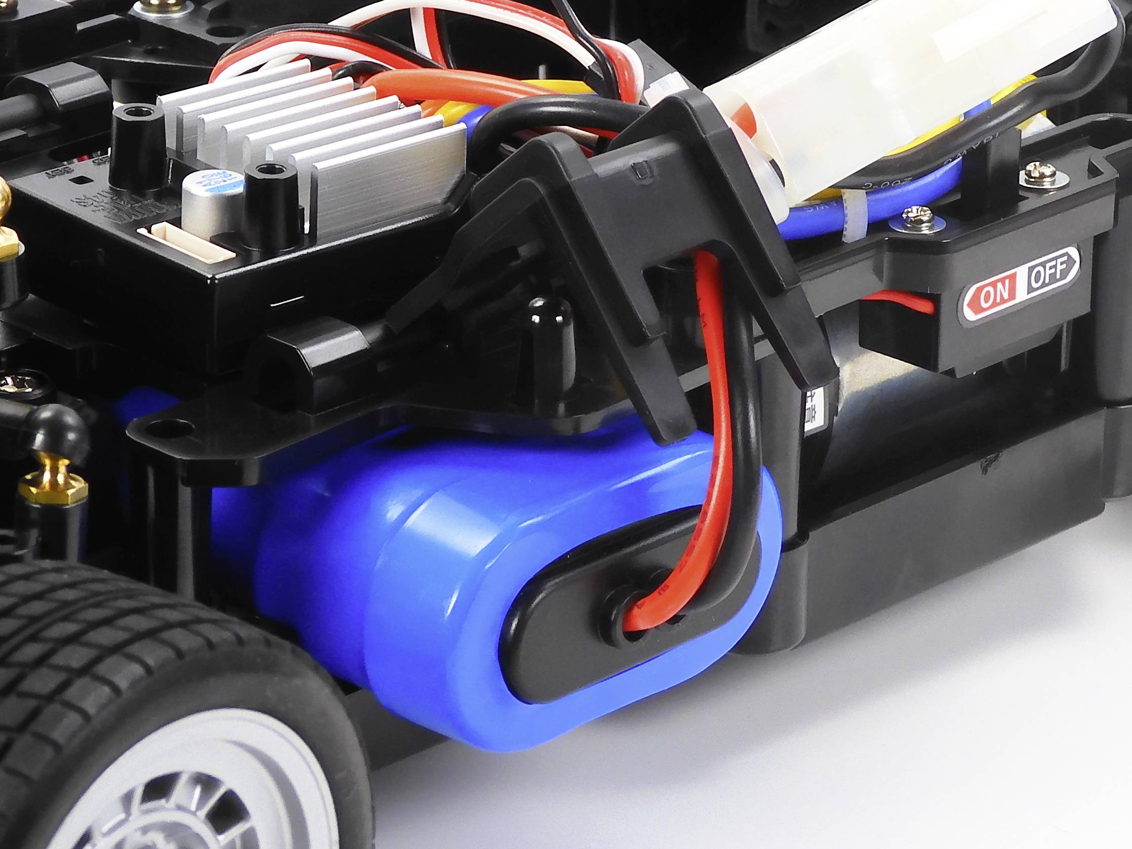 Nahaufnahme eines ferngesteuerten Auto-Chassis mit sichtbarer Verkabelung und Schalter für Ein/Aus.