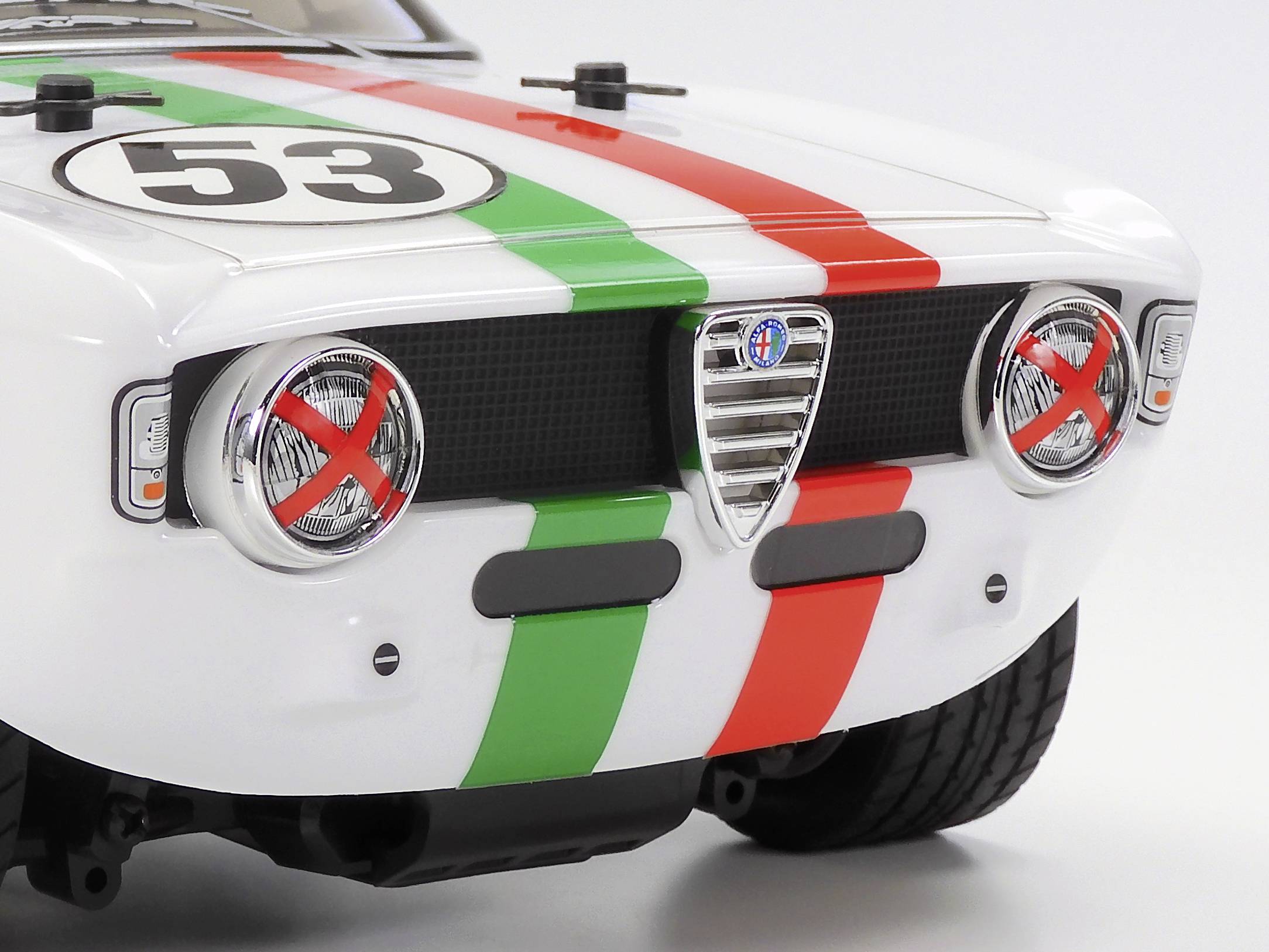 Weißer Sportwagen mit grünen und roten Streifen und der Nummer '53'. Vorderseite mit abgeklebten Scheinwerfern in einem Rallye-Stil.