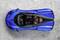 Blaues Sportauto von oben auf grauem Hintergrund, zeigt elegantes Design und aerodynamische Form.