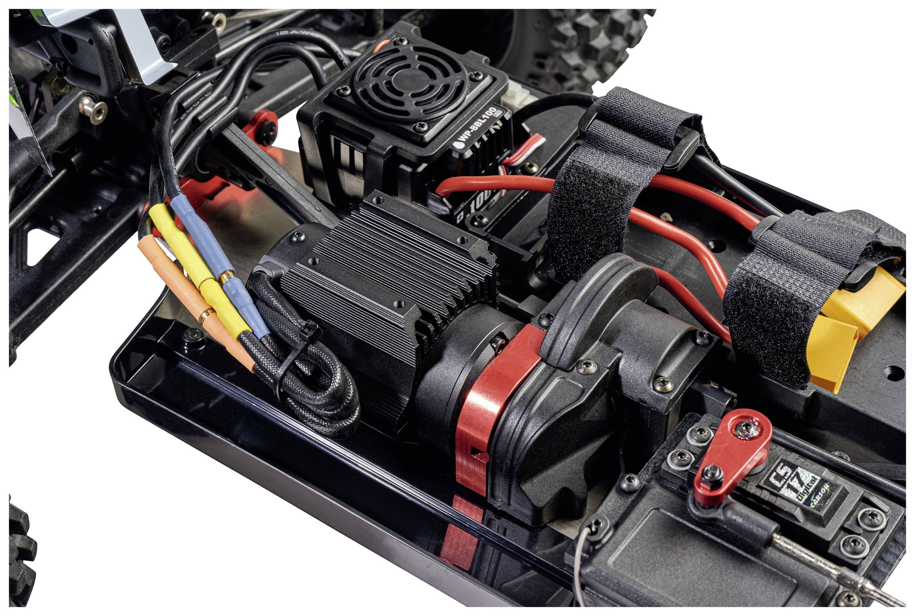 Nahaufnahme eines ferngesteuerten Auto-Chassis mit Kabeln, elektrischen Komponenten und einem schwarzen Kühlkörper.