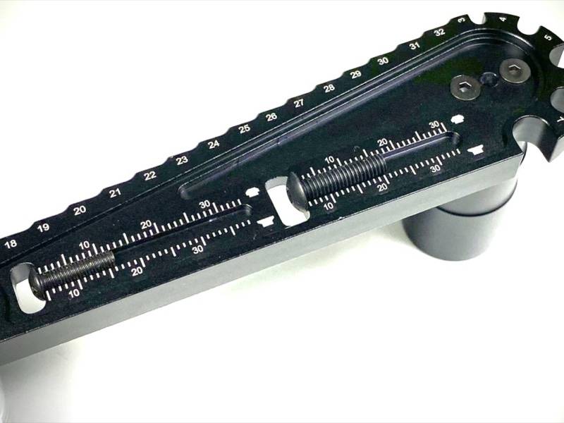 Ein schwarzes mechanisches Gerät mit Skalen und Schiebern. Die Skalen sind nummeriert von 18 bis 33.