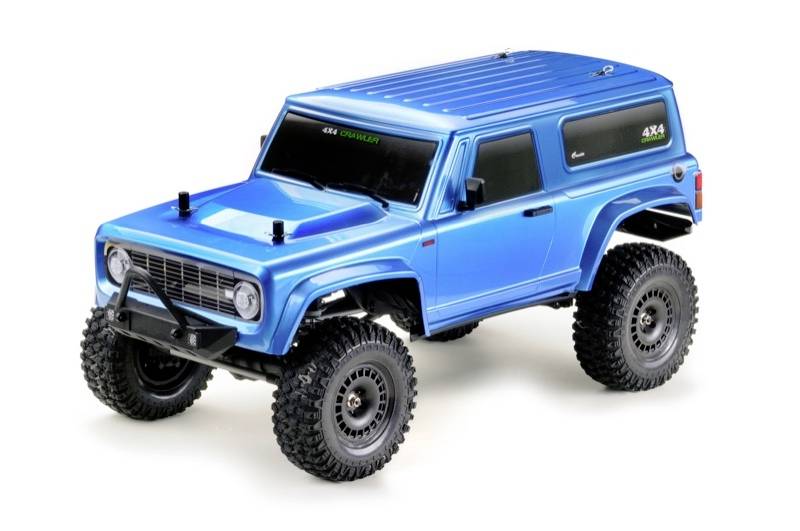 Ein blaues ferngesteuertes Auto im Offroad-Stil mit großen Reifen und einem stabilen Karosseriedesign steht auf einer weißen Oberfläche.