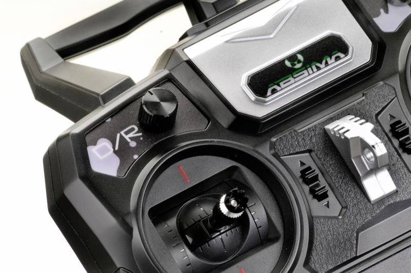 Nahaufnahme einer schwarzen Fernbedienung für Modellfahrzeuge mit mehreren Knöpfen und Hebeln zur Steuerung, unten links roter Punkt.