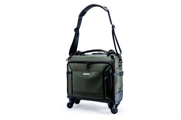 Grüne Reisetasche mit schwarzem Trageriemen und Rollen auf weißem Hintergrund.