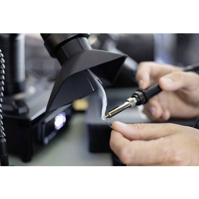 Nahaufnahme von Händen beim Löten einer kleinen elektronischen Komponente unter einem Mikroskop, mit einem Lötkolben und freiliegendem Draht.