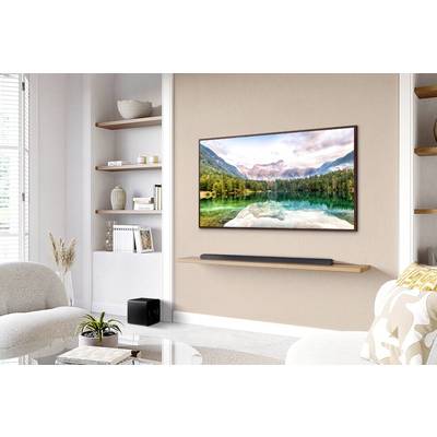 Wohnzimmer mit beige Sofa, moderner Wandregal, Flachbildfernseher, zeigt Bergsee-Landschaft. Dezentes, stilvolles Dekor.