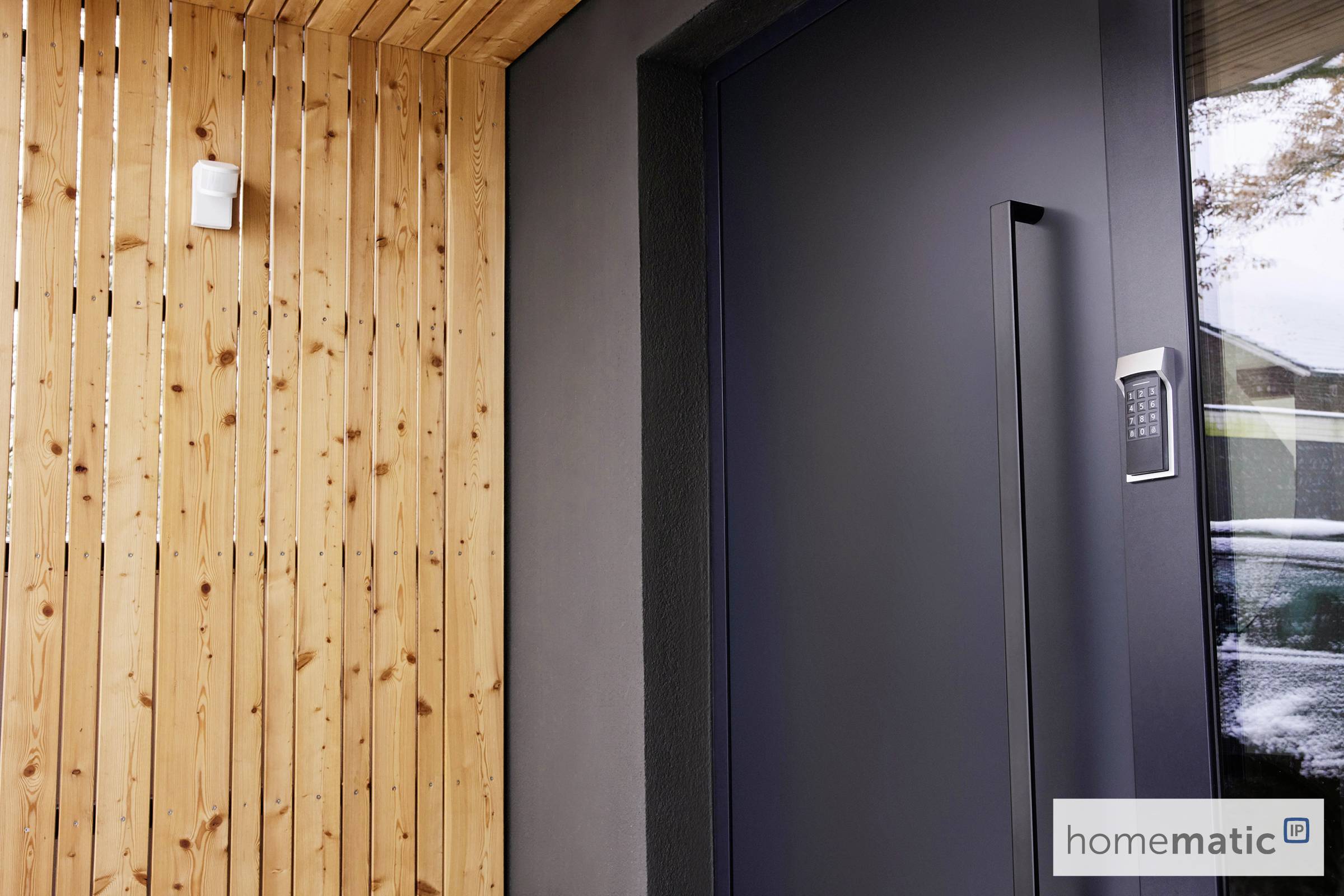 Moderne Eingangstür mit Zugangskontrollsystem neben Holzverkleidung.