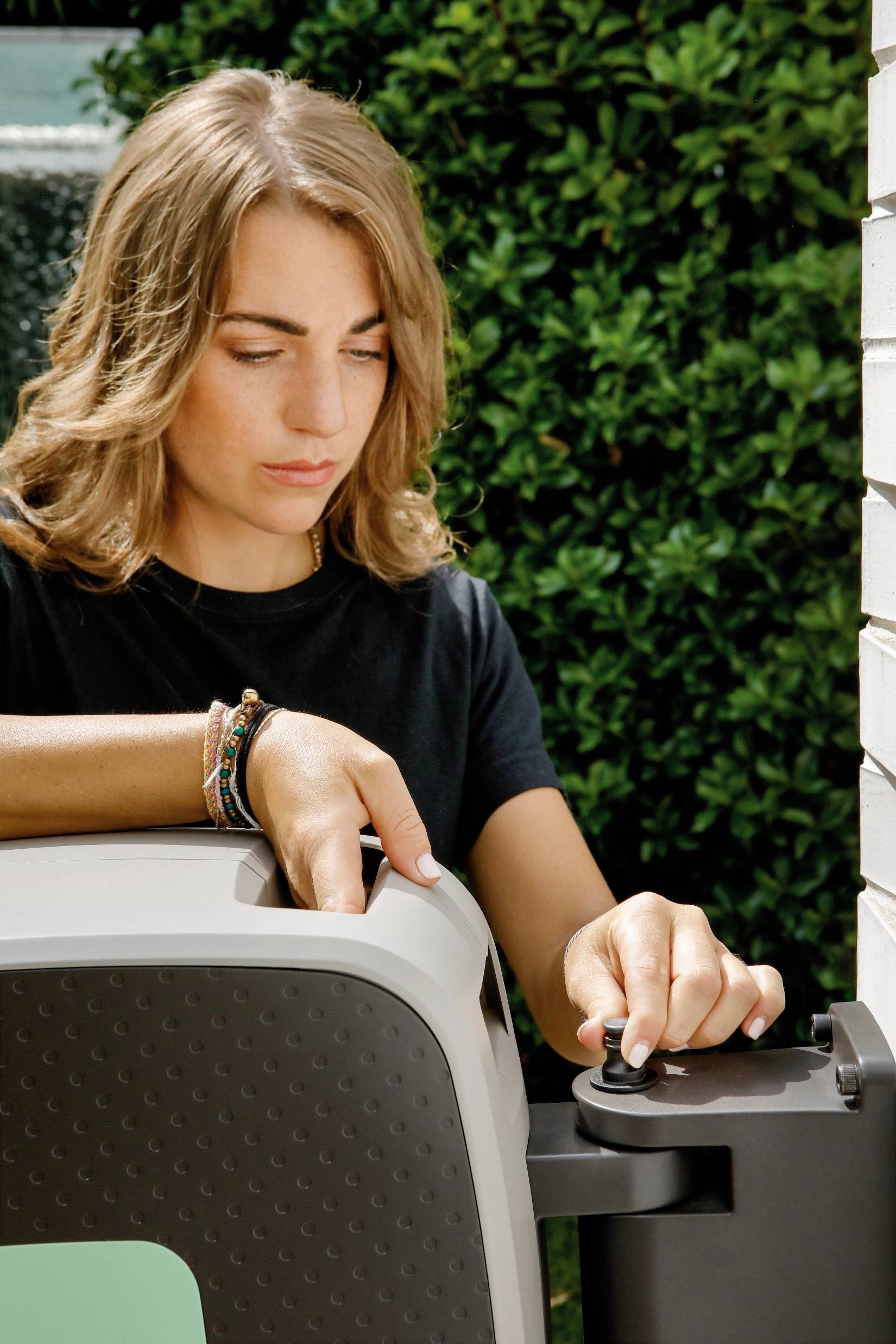 Eine Person steht draußen neben einer Ladestation und hält ein Elektroauto-Kabel. Sie schaut auf den Ladevorgang.