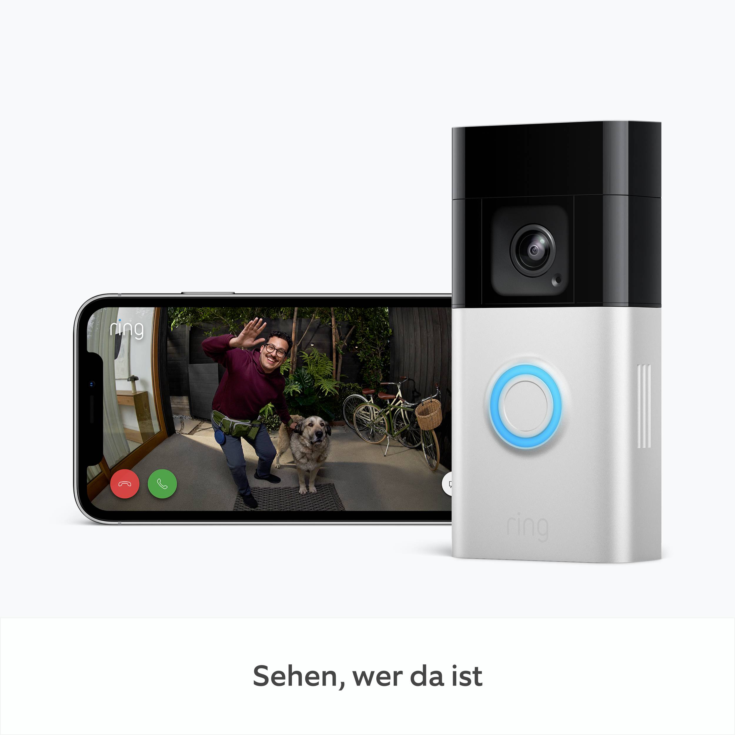 Eine Person lächelt und winkt in eine Kamera. Ein Smartphone zeigt das Bild der Person und eines Hundes neben Fahrrädern. Text: 'Sehen, wer da ist'.