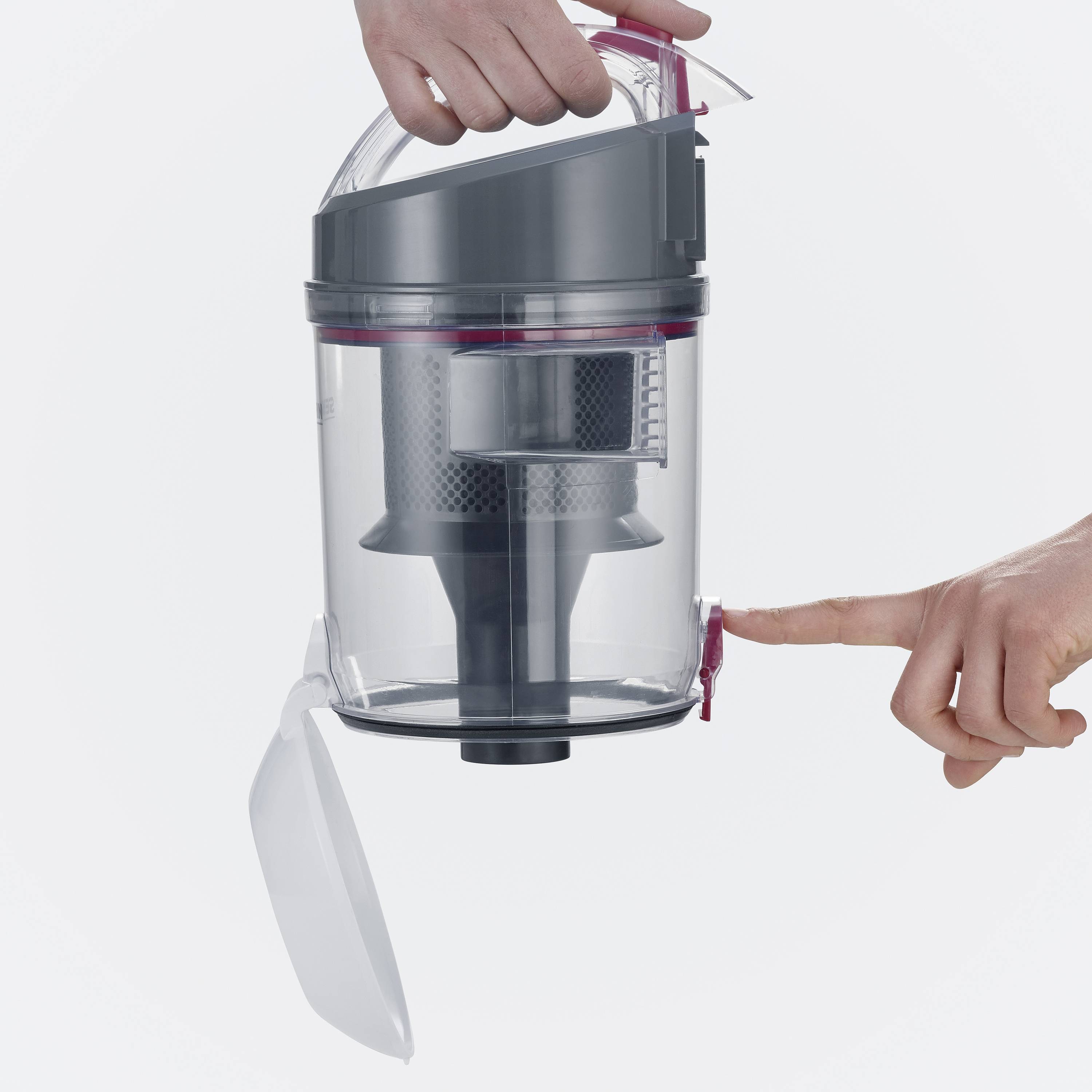 Ein Staubsaugerbehälter wird von einer Hand gehalten, während eine andere Hand den Deckel öffnet. Der Behälter ist durchsichtig.