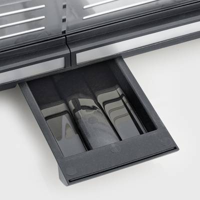 Ein schwarzer, herausgezogener Ablagebehälter unter einem grauen Gerät, möglicherweise ein Toaster. Der Behälter scheint abnehmbar zu sein.