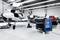 Ein kleines Flugzeug in einem Hangar mit geöffnetem Cockpit und ein blauer Werkzeugwagen auf Rollen im Vordergrund.