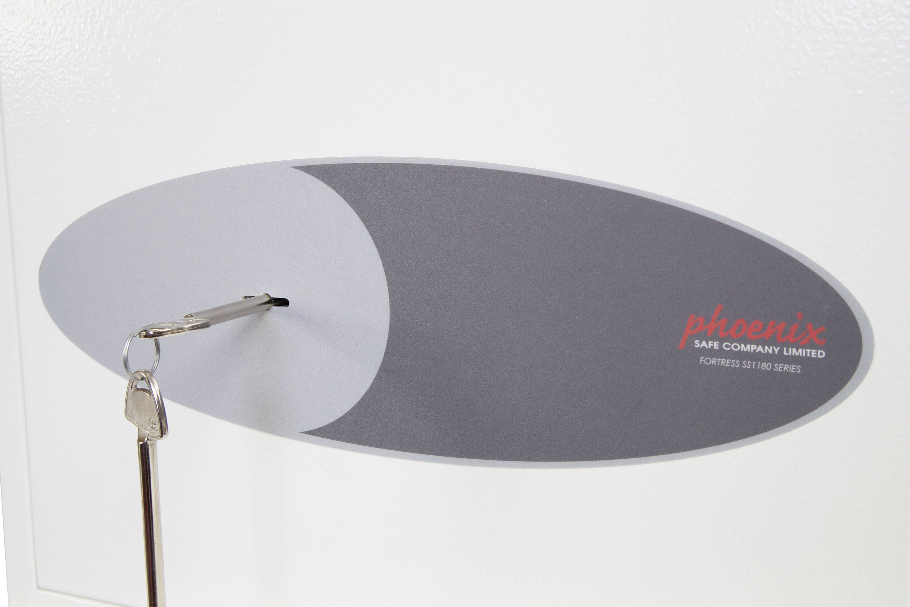 Ein ovales Schild auf einem Safe zeigt das Firmenlogo 'phoenix Safe Company Limited'. Ein Schlüssel steckt im Safe.