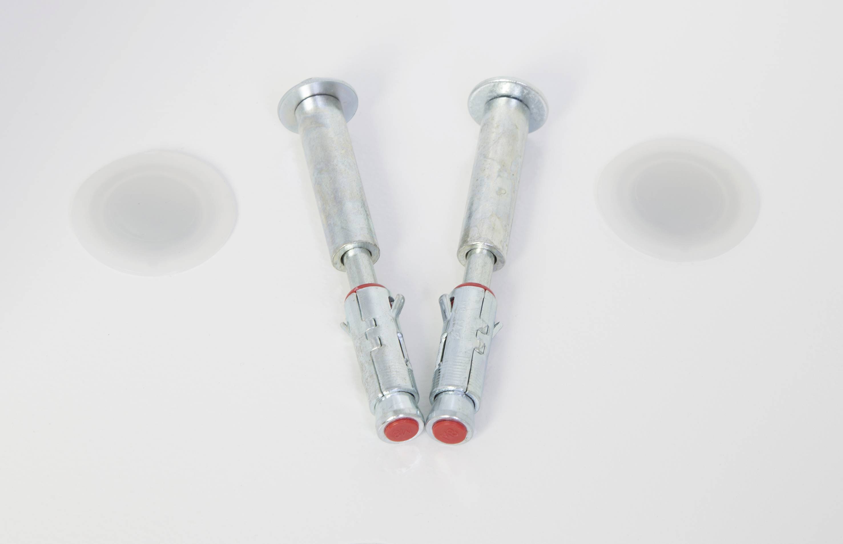 Zwei Metallspreizdübel auf weißem Hintergrund, die zum Befestigen schwerer Gegenstände an Wänden verwendet werden.