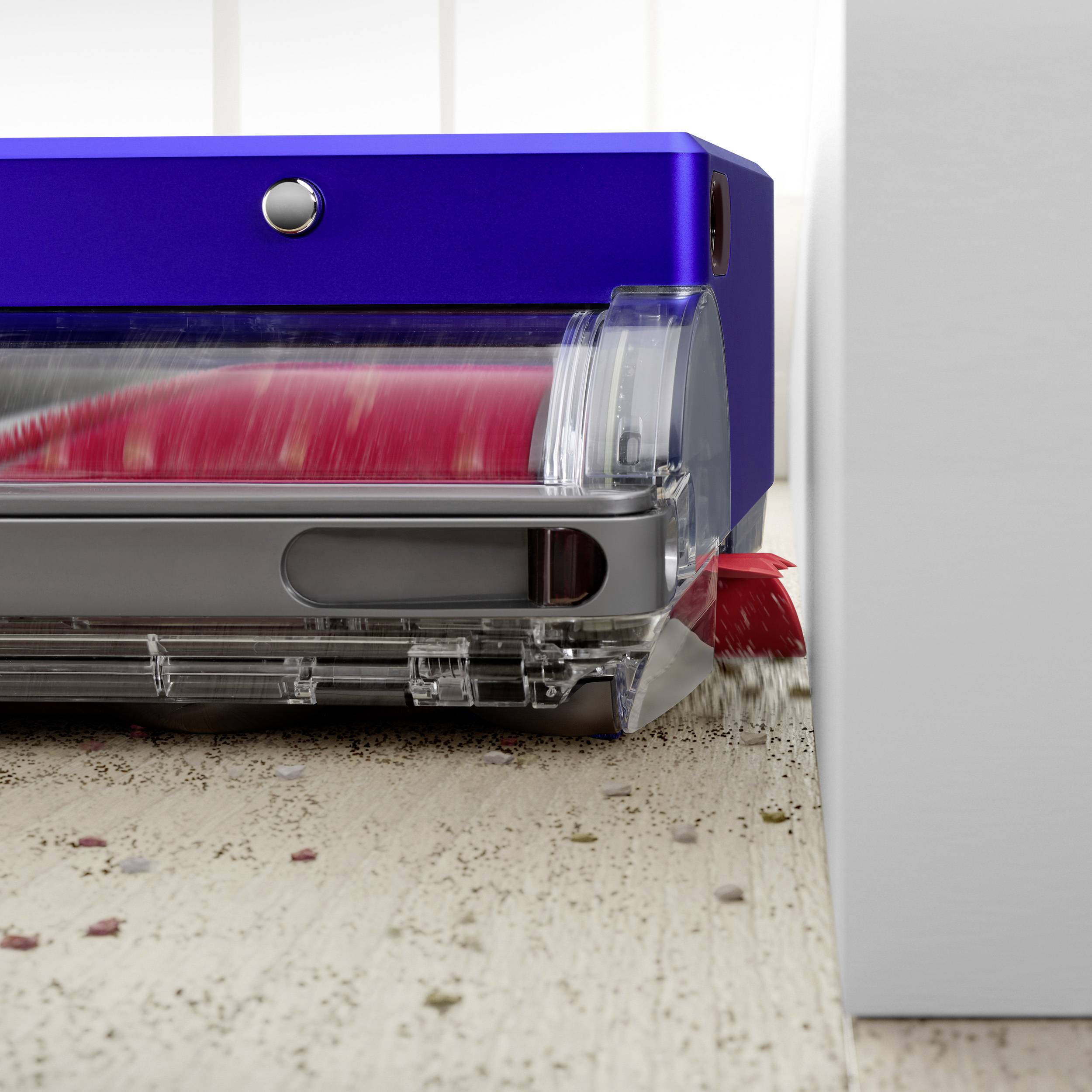 Ein Roboter-Staubsauger reinigt einen Holzboden, indem er Schmutz und Krümel aufsaugt. Der blaue Roboter ist im Einsatz.