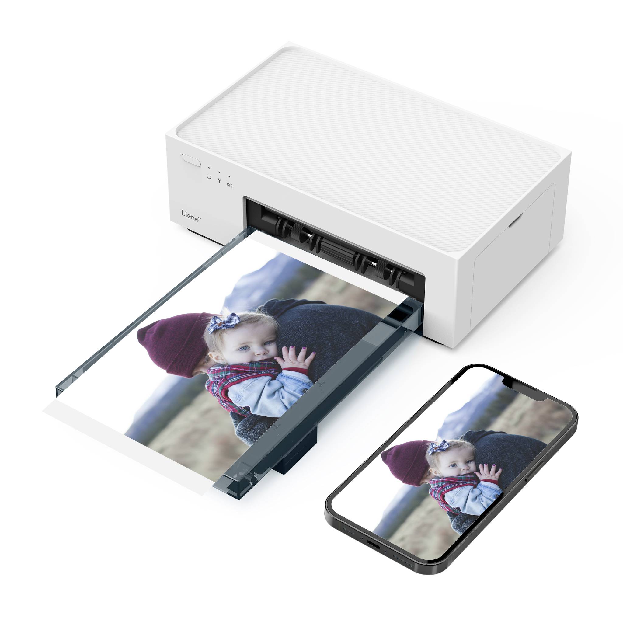 Ein Drucker druckt ein Foto eines Kindes in roter Mütze, das von einer Person gehalten wird. Daneben liegt ein Smartphone mit demselben Bild.