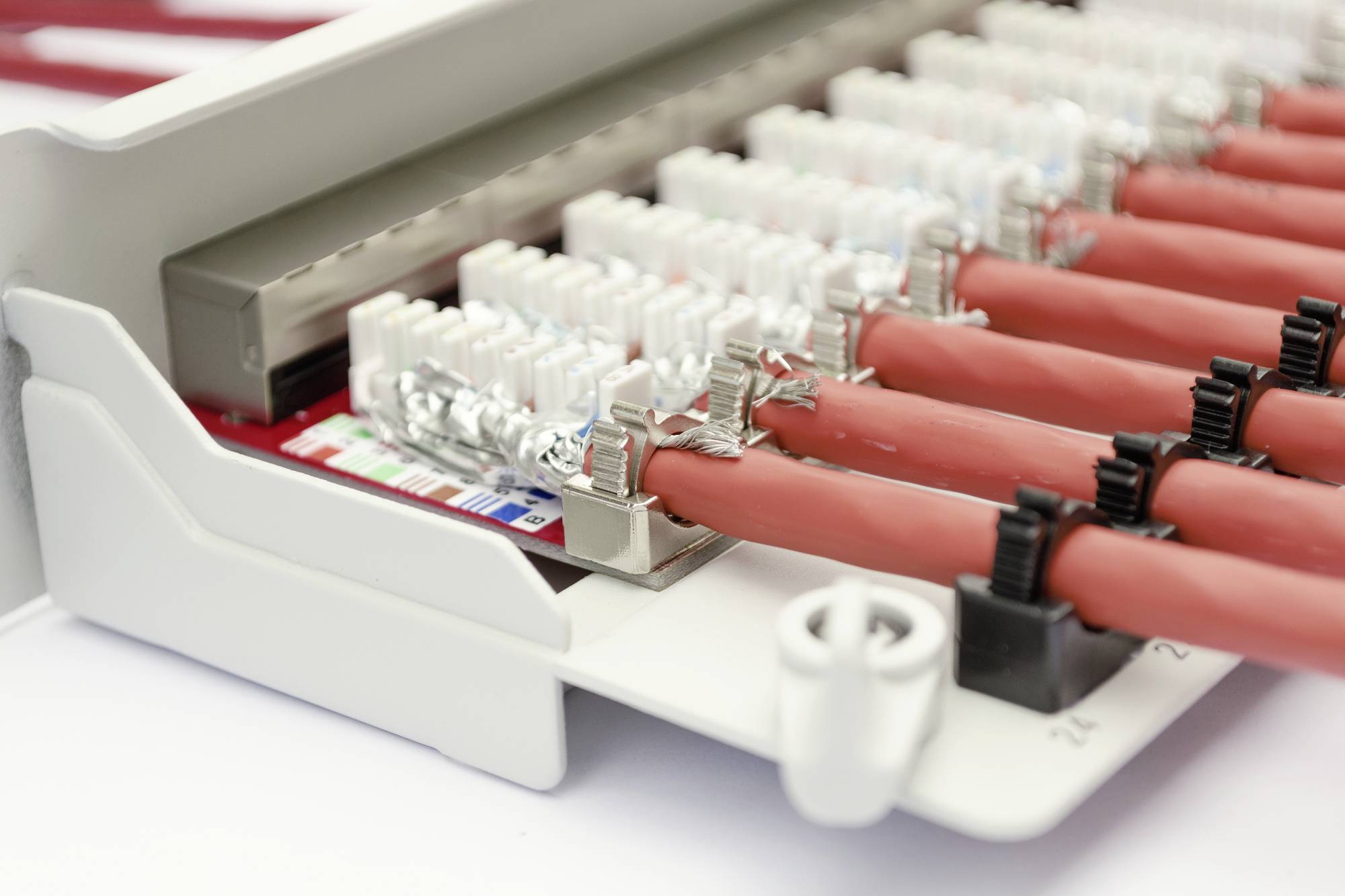 Ein Telekommunikationsverteiler mit roten Kabeln und weißen Verbindungsklemmen zeigt die Verkabelung für Netzwerkverbindungen.