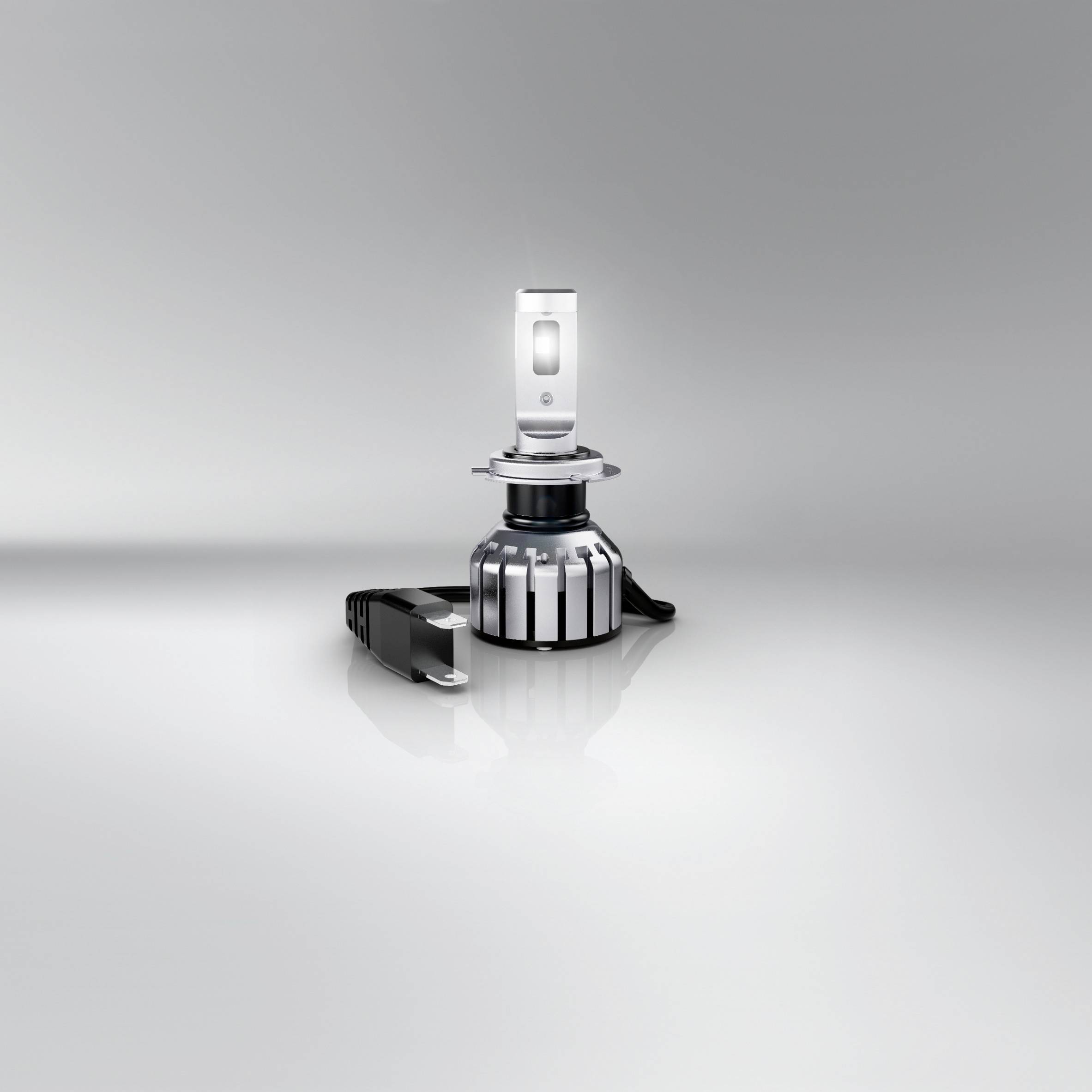 LED-Autolampe mit metallischem Gehäuse und Kühlkörper, auf grauem Hintergrund platziert. Beinhaltet eine Halterung als Zubehör.