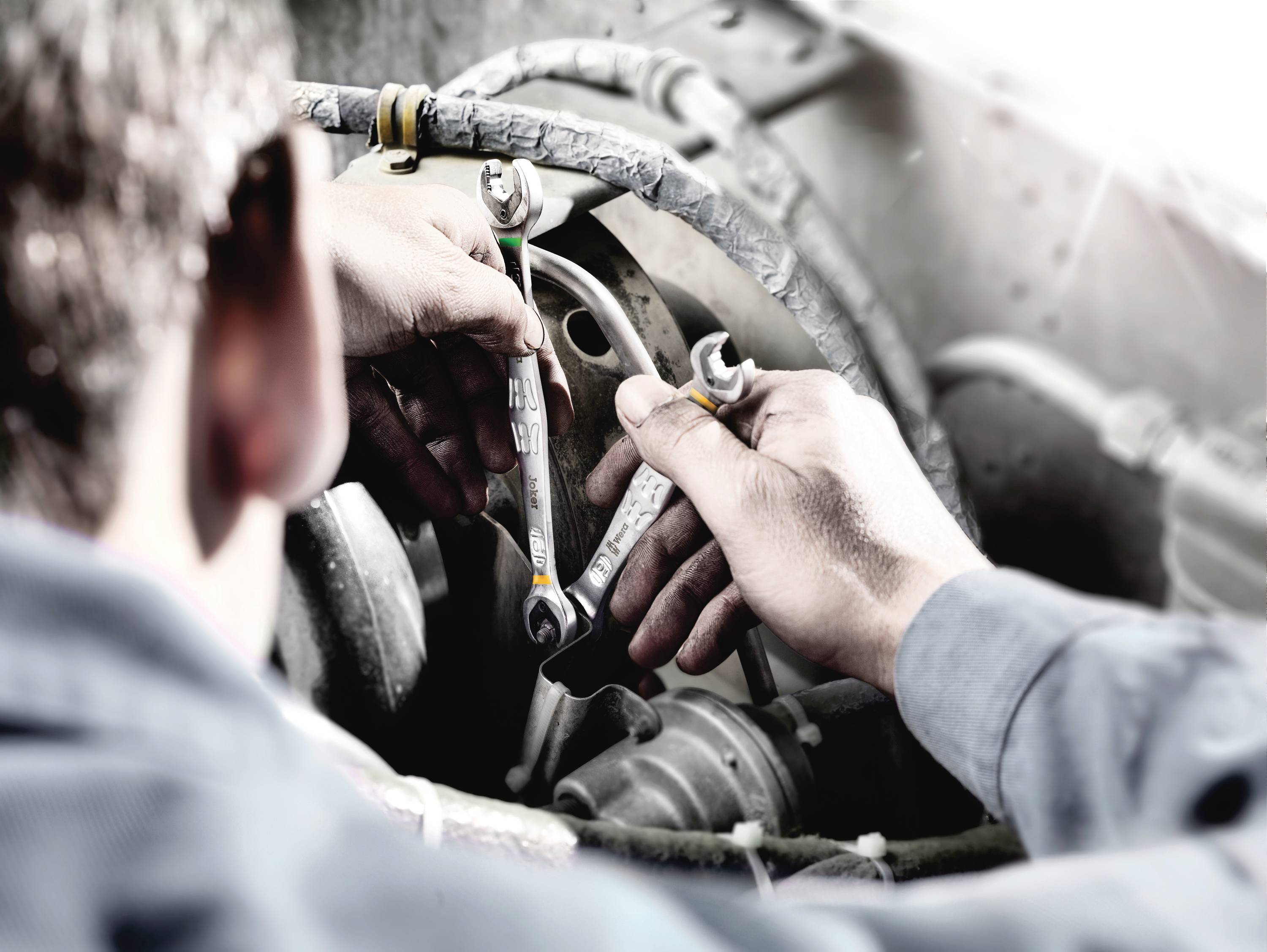 'Mechaniker arbeitet mit Schraubenschlüsseln an einem Motor.'