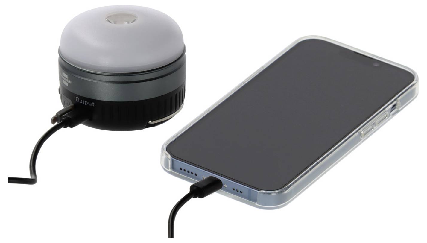 Ein Smartphone wird über ein Kabel geladen, das mit einer kleinen tragbaren Powerbank mit gewölbter Oberseite verbunden ist.
