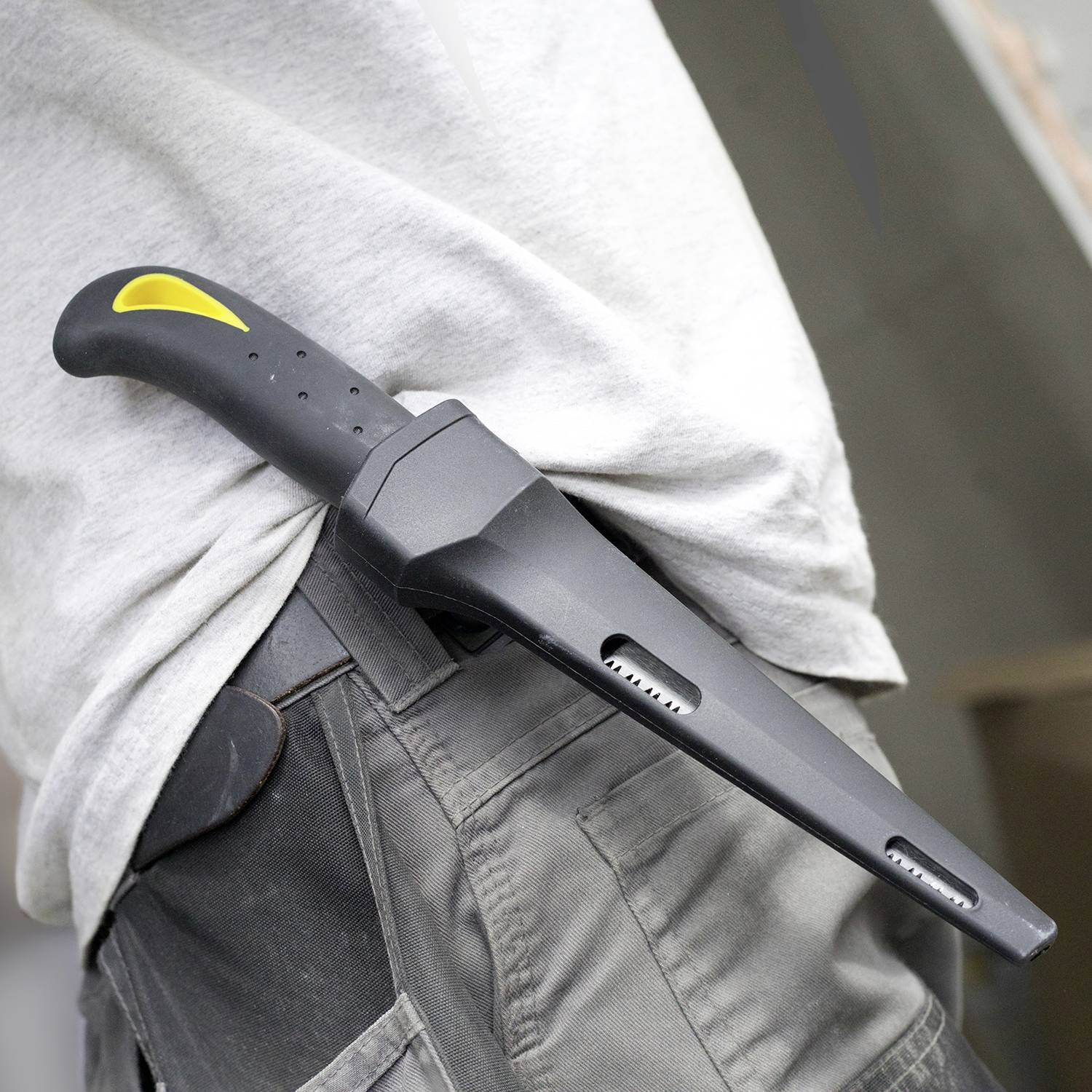 Ein Messer in einem schwarzen und gelben Halfter ist an einer Person in grauer Hose befestigt und sichtbar an der Hüfte getragen.