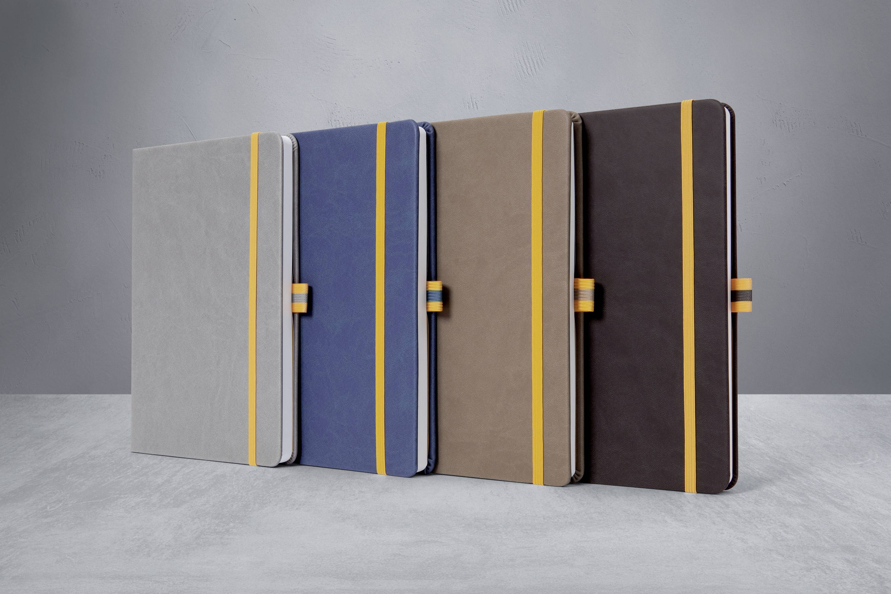 Vier Notizbücher in unterschiedlichen Farben (Grau, Blau, Braun, Dunkelbraun) stehen in einer Reihe; jedes hat ein gelbes Band.