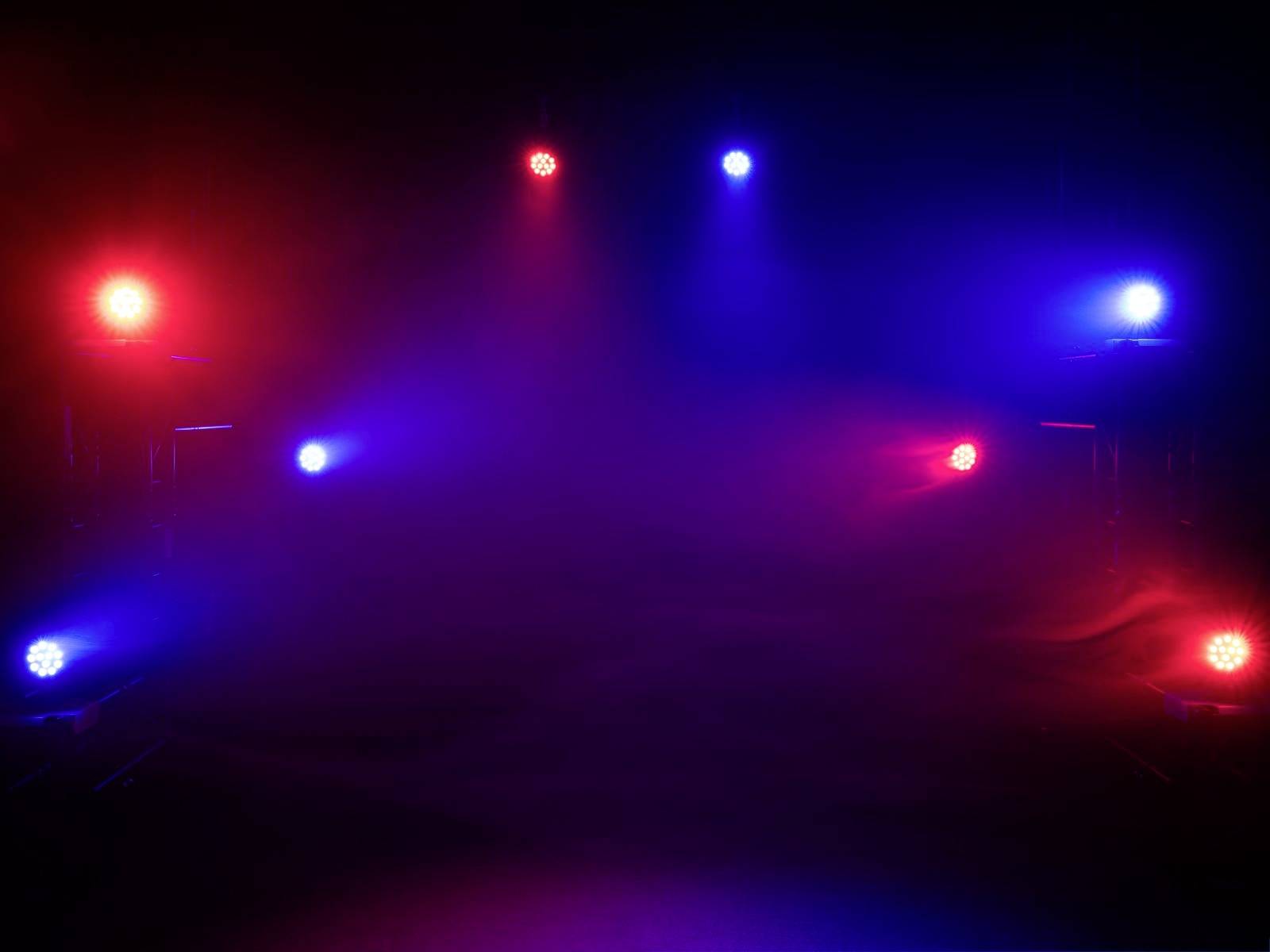 Bühne mit farbigen Lichtern in Blau und Rot, die auf einen nebligen Hintergrund strahlen, wodurch eine stimmungsvolle Atmosphäre entsteht.
